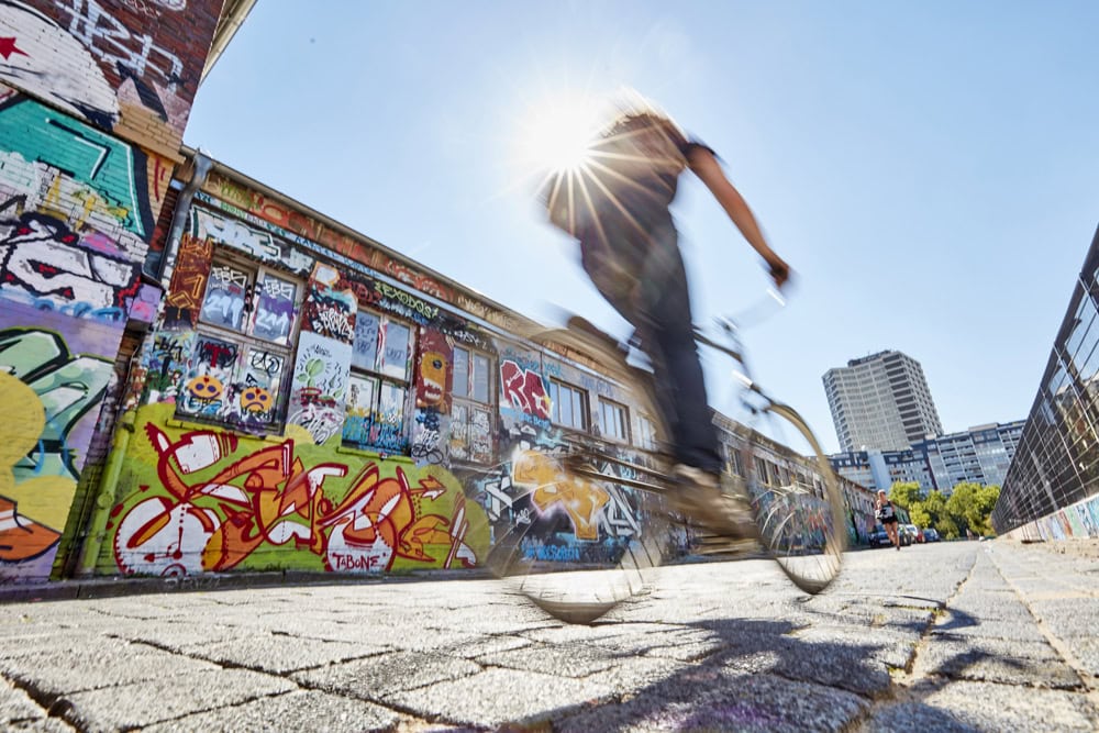 Ein Fahrradfahrer fährt auf das Ihme-Zentrum zu. Neben ihm auf einer Wand sind viele bunte Graffitis