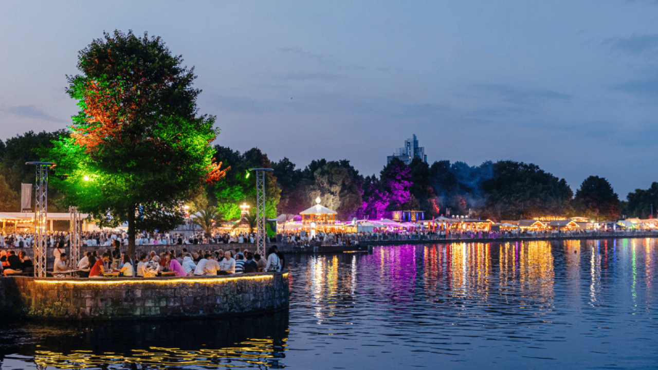 Abendliches Fest am See mit bunten Lichtern, vielen Menschen und stimmungsvoller Spiegelung im Wasser beim Maschseefest 2025.